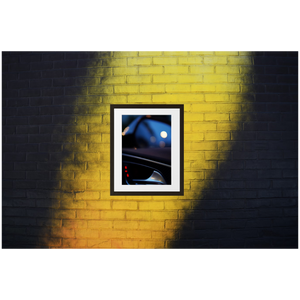 Framed Photo Print Poster "RS6 Blurr" on black & yellow brick wall. Shows a bokeh version of the inside of a Audi RS6 door. Moody Photography by Jacob Sellström. Printed on matte paper with wooden frame. Two sizes: 8x10, 12x16.